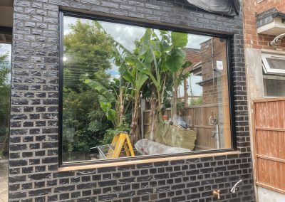 Fixed aluminium window in a black brick extension
