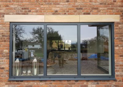 Grey tilt and turn windows in a brick wall