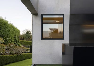 Dark aluminium hidden-sash window in a render wall